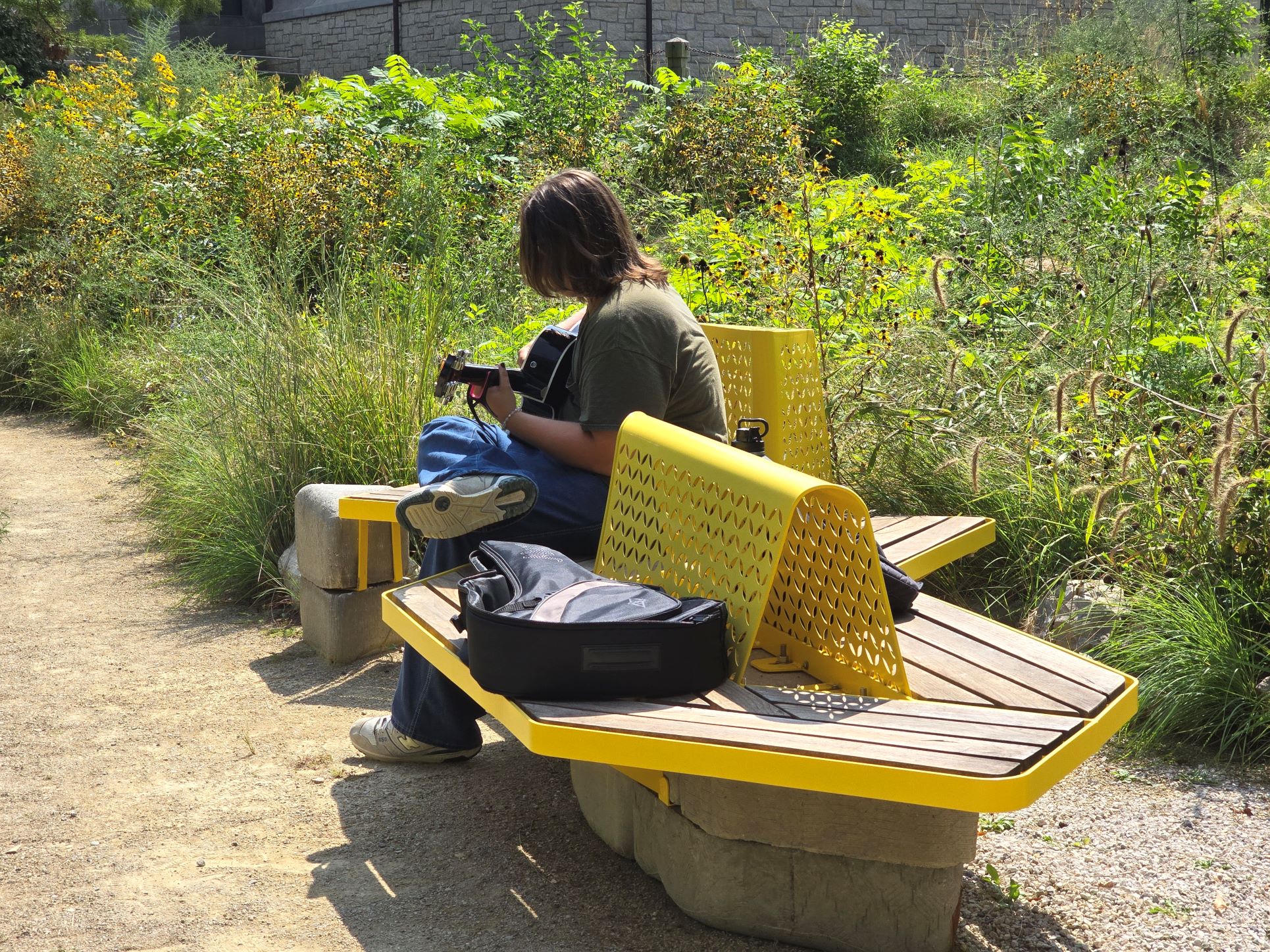 Student playing guitar while seated on one of the three Meadow seating elements.